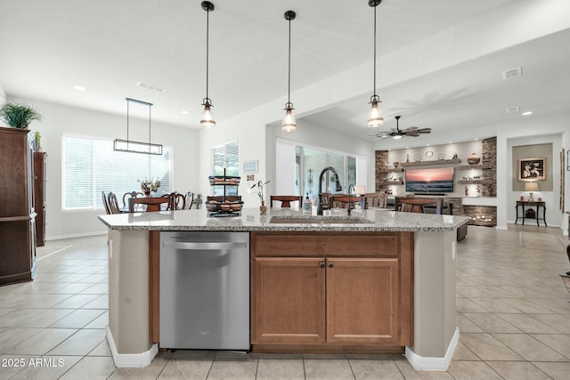 kitchen featuring decorative light fixtures, dishwasher, sink, a kitchen island with sink, and light stone counters