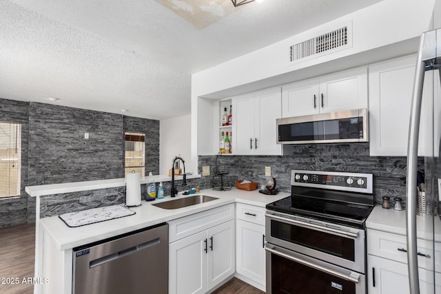 3829 W Camino Del Rio, Glendale, AZ 85310 - kitchen with appliances with stainless steel finishes, a sink, a peninsula, a textured ceiling, and wood finished floors