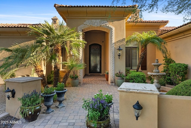 view of exterior entry with a tile roof and stucco siding