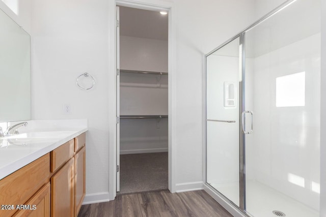 bathroom with walk in shower, vanity, and hardwood / wood-style floors