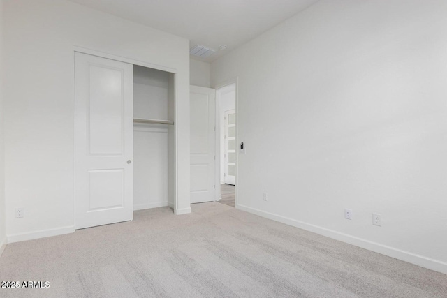 unfurnished bedroom featuring light colored carpet and a closet