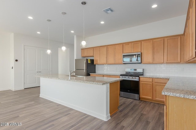 kitchen featuring light stone counters, backsplash, stainless steel appliances, and an island with sink