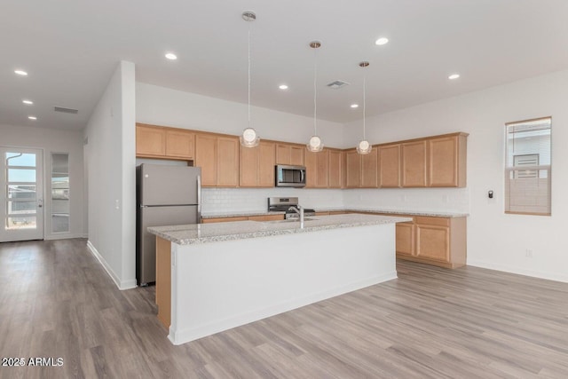 kitchen featuring appliances with stainless steel finishes, pendant lighting, tasteful backsplash, sink, and a center island with sink