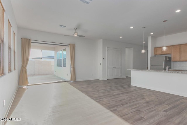 unfurnished living room with ceiling fan and light wood-type flooring