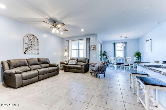 tiled living room with ceiling fan with notable chandelier