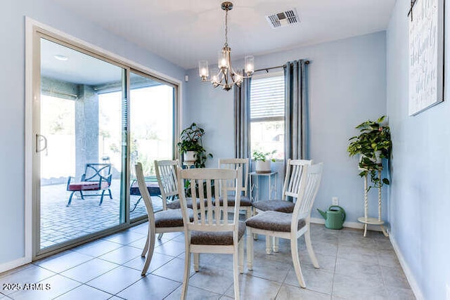 tiled dining room with a healthy amount of sunlight and a notable chandelier