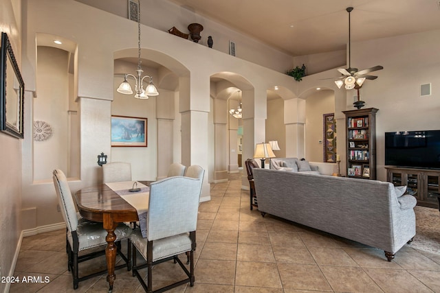 tiled dining space with ceiling fan with notable chandelier and a towering ceiling