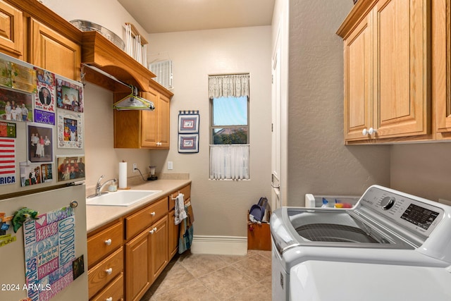 laundry area featuring separate washer and dryer, sink, light tile patterned flooring, and cabinets