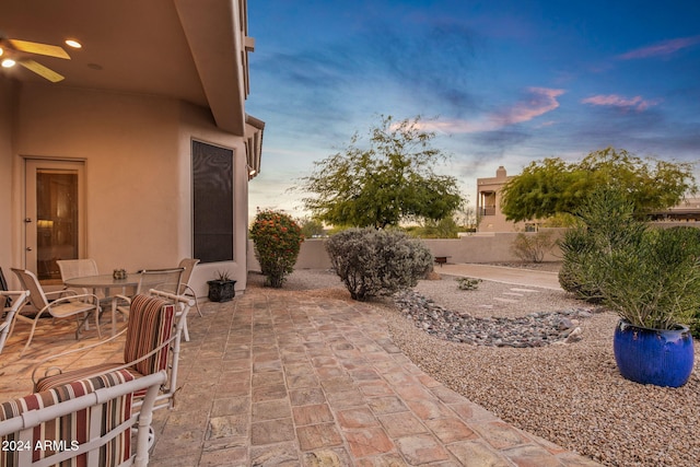 patio terrace at dusk featuring ceiling fan