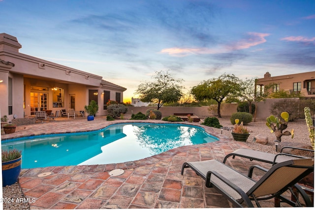 pool at dusk featuring a patio