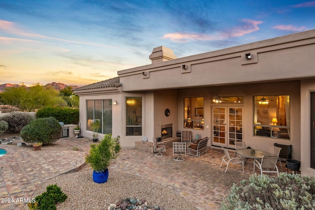 back house at dusk with a patio and exterior fireplace