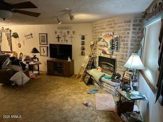 living room with carpet floors, rail lighting, a fireplace, and ceiling fan