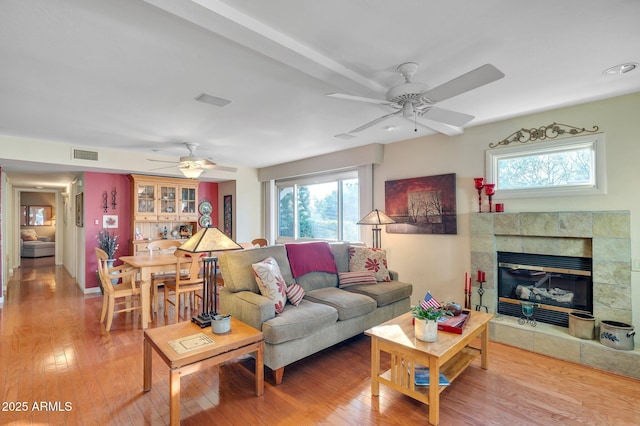 living room featuring a tiled fireplace, hardwood / wood-style floors, and ceiling fan