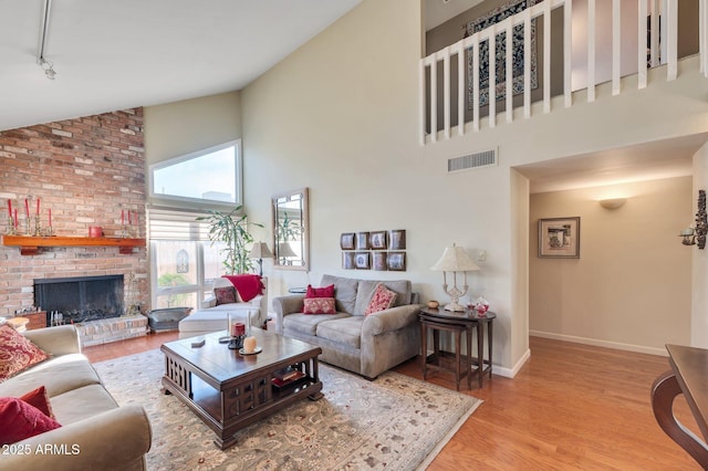 living room with high vaulted ceiling, a fireplace, and light hardwood / wood-style flooring