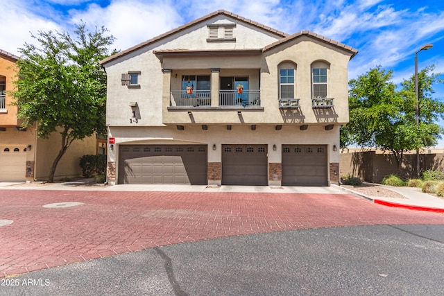 view of property featuring fence, a garage, stucco siding, decorative driveway, and a balcony