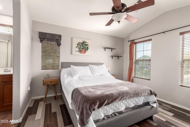 bedroom with a ceiling fan, vaulted ceiling, wood finished floors, a sink, and baseboards
