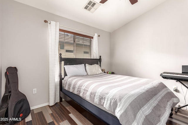 bedroom with a ceiling fan, visible vents, vaulted ceiling, wood finished floors, and baseboards