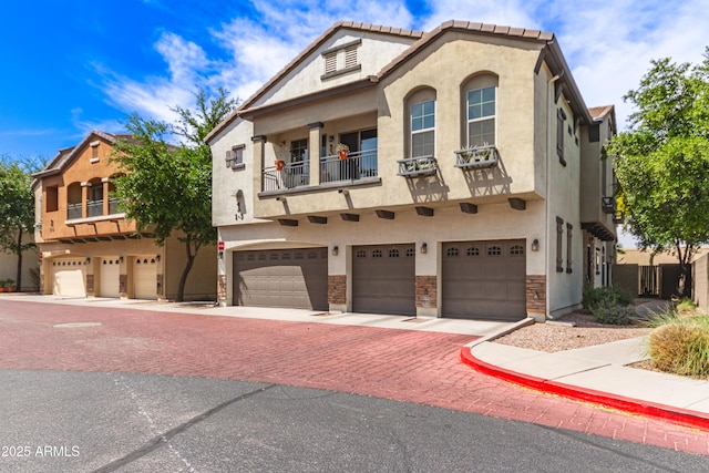 view of front of property featuring stucco siding, driveway, a balcony, and a garage