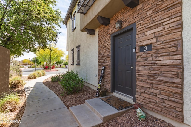 property entrance with stucco siding and stone siding