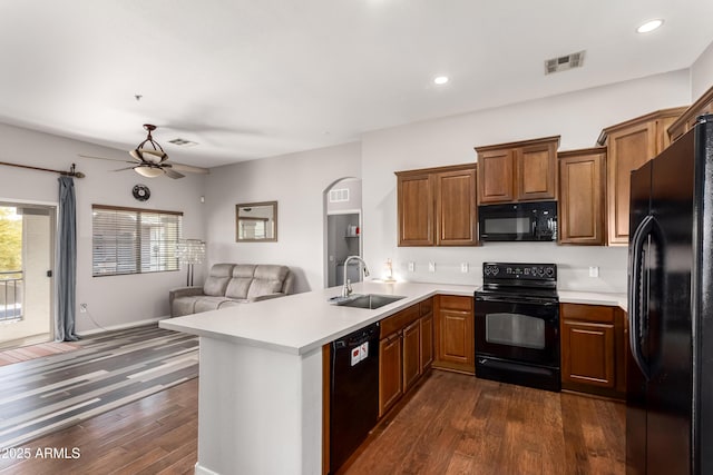kitchen featuring dark wood-style flooring, a sink, black appliances, a peninsula, and open floor plan