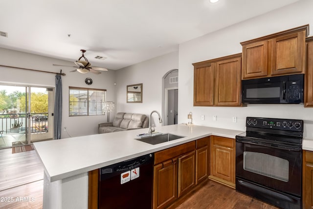 kitchen featuring a sink, light countertops, a peninsula, open floor plan, and black appliances