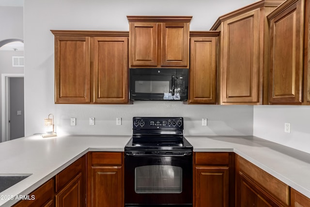 kitchen with visible vents, light countertops, arched walkways, and black appliances