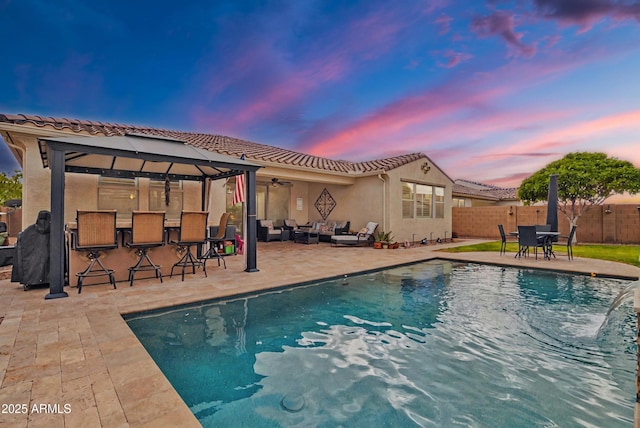 view of pool featuring a fenced in pool, fence, an outdoor living space, a patio area, and outdoor dry bar