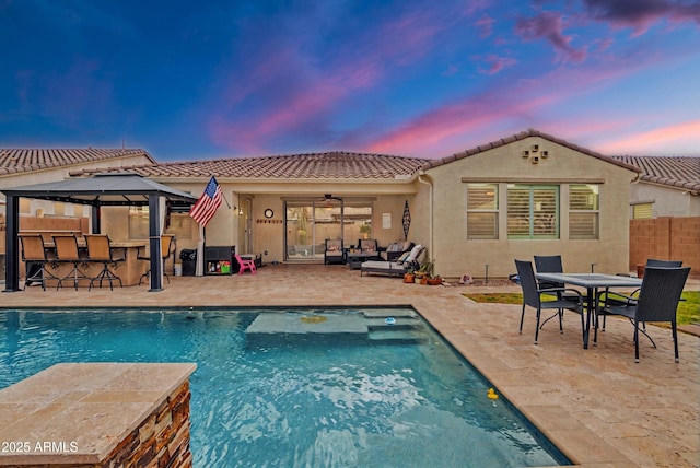 rear view of property with outdoor dry bar, a patio, fence, outdoor lounge area, and a fenced in pool