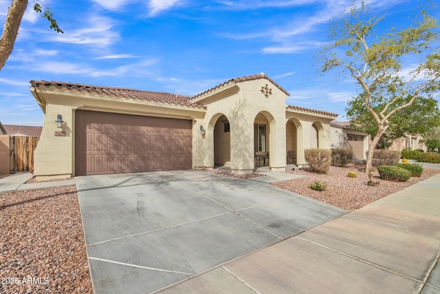 mediterranean / spanish-style house with a tile roof, an attached garage, driveway, and stucco siding