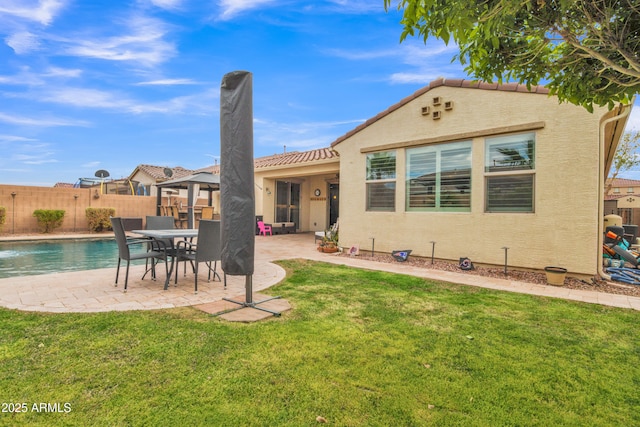 back of property with stucco siding, a patio, a lawn, and fence