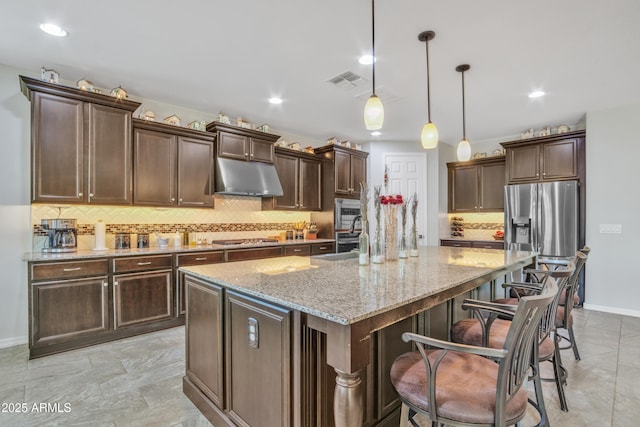 kitchen featuring visible vents, dark brown cabinets, under cabinet range hood, light stone counters, and stainless steel appliances