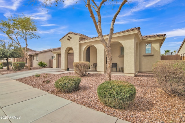 mediterranean / spanish home with stucco siding, a porch, concrete driveway, and a tiled roof