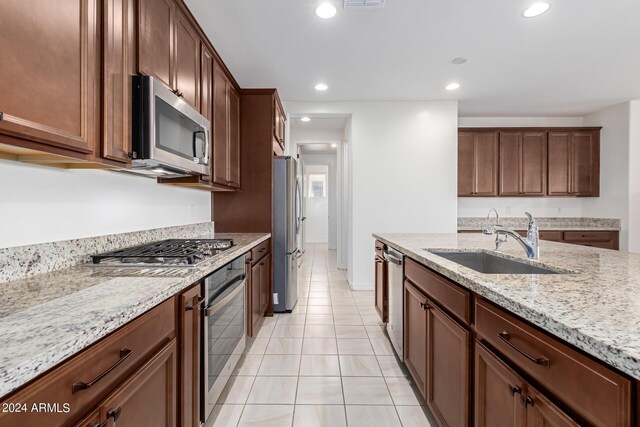 kitchen featuring appliances with stainless steel finishes, light stone counters, sink, and light tile patterned flooring