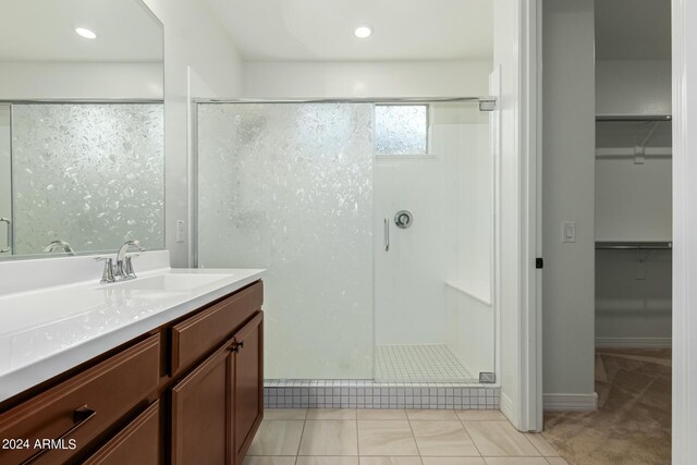 bathroom featuring tile patterned floors, a shower with door, and vanity