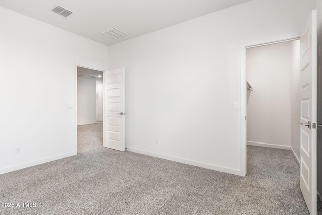 unfurnished bedroom with a spacious closet, carpet floors, and a closet