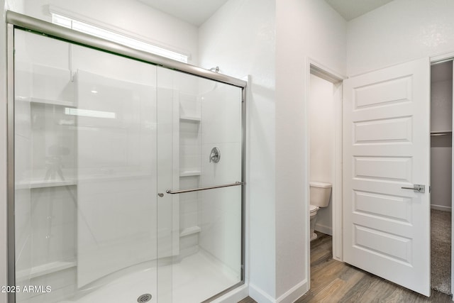 bathroom featuring hardwood / wood-style flooring, a shower with shower door, and toilet