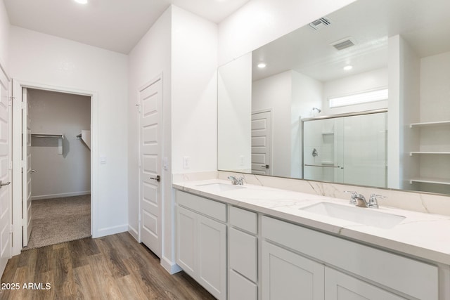 bathroom with wood-type flooring, vanity, and a shower with shower door