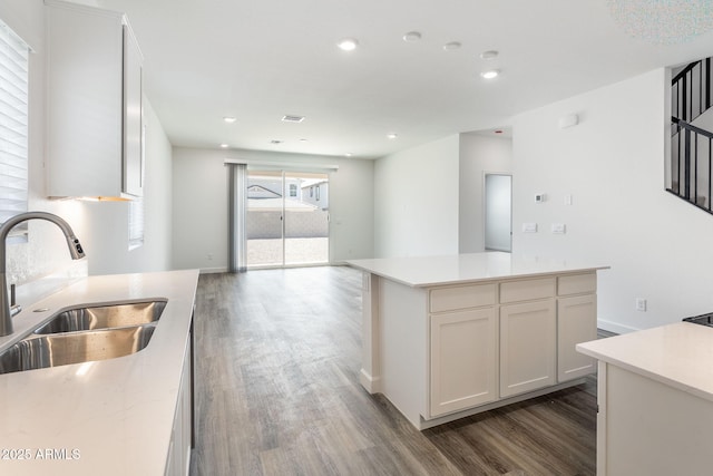 kitchen featuring a center island, sink, dark wood-type flooring, and white cabinets