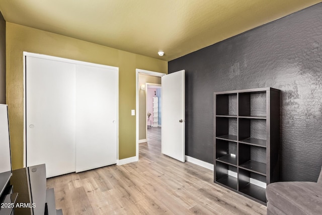 12517 W Santa Fe Ln, El Mirage, AZ 85335 - unfurnished bedroom featuring baseboards, wood finished floors, and a closet