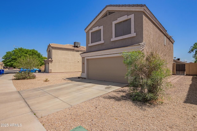 12517 W Santa Fe Ln, El Mirage, AZ 85335 - view of home's exterior featuring an attached garage, a tiled roof, driveway, and stucco siding