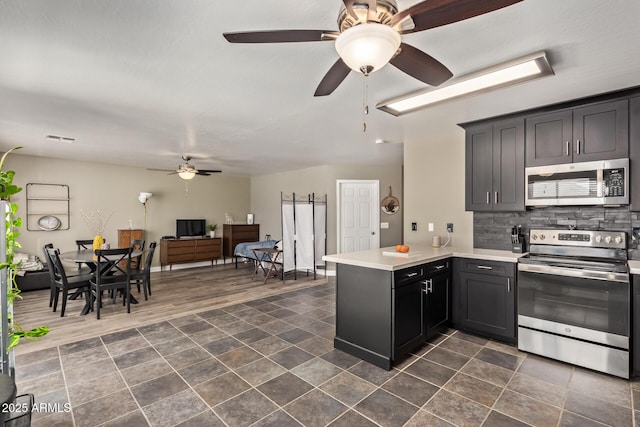 12517 W Santa Fe Ln, El Mirage, AZ 85335 - kitchen with visible vents, a ceiling fan, decorative backsplash, a peninsula, and appliances with stainless steel finishes