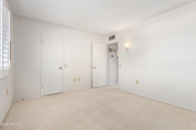 19402 N Welk Dr, Sun City, AZ 85373 - unfurnished bedroom with visible vents, baseboards, light colored carpet, and a textured ceiling