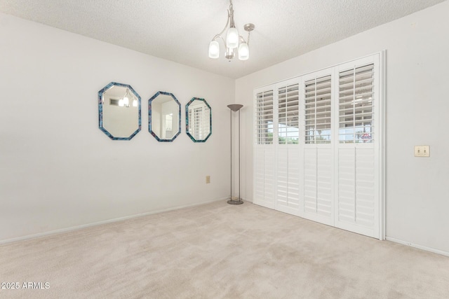 19402 N Welk Dr, Sun City, AZ 85373 - spare room featuring a chandelier, a textured ceiling, light colored carpet, and baseboards
