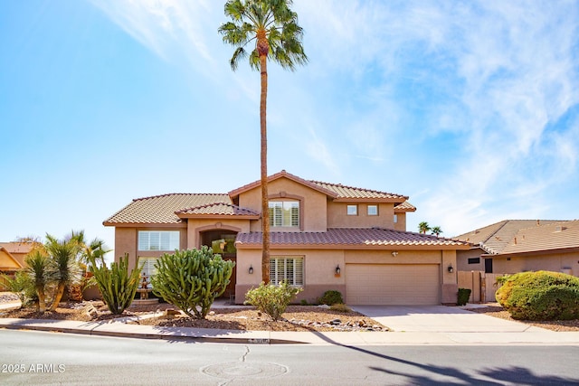 mediterranean / spanish house featuring driveway, a tiled roof, a garage, and stucco siding