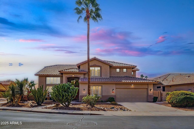 mediterranean / spanish-style home with driveway, a tile roof, a garage, and stucco siding