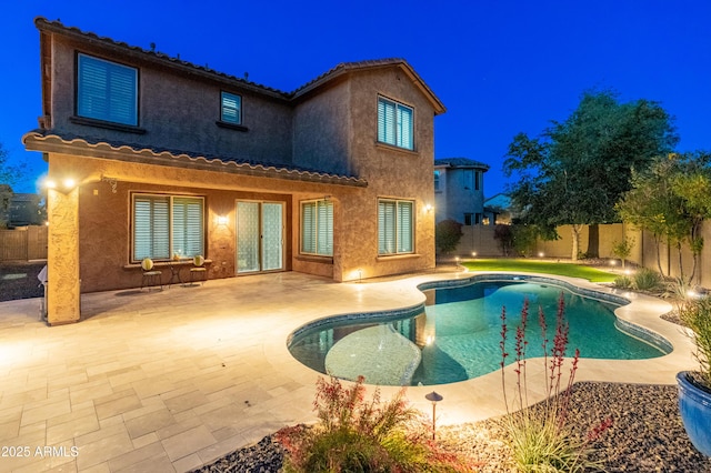 3603 E Salter Dr, Phoenix, AZ 85050 - back of house at night featuring stucco siding, a fenced in pool, a patio, and a fenced backyard