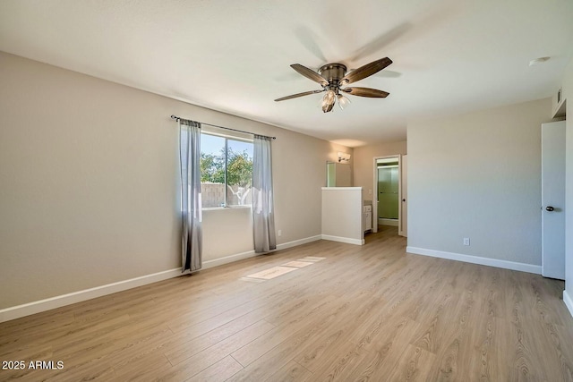 spare room with baseboards, light wood-style floors, and a ceiling fan