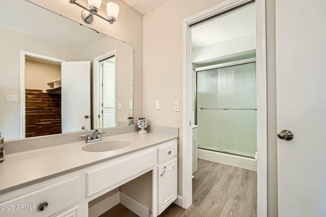 bathroom with a stall shower, vanity, and wood finished floors