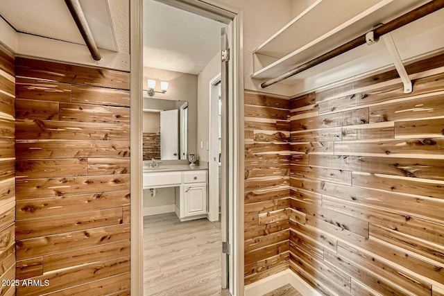 bathroom with wooden walls, vanity, and wood finished floors