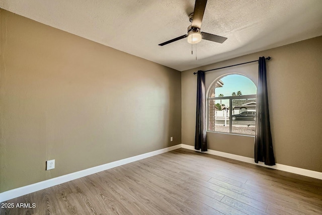 unfurnished room with ceiling fan, wood finished floors, baseboards, and a textured ceiling